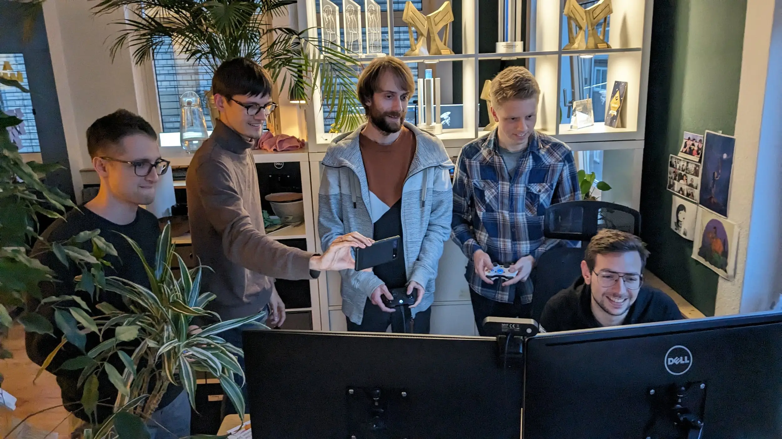The team gathered around a monitor, playtesting with controllers in the studio